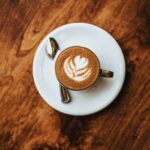 A top-down view of cappuccino with latte art, placed on a rustic wooden table.
